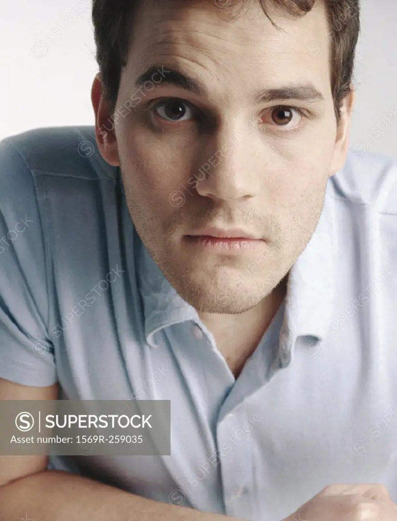 Young man with eyebrow raised looking at camera, close-up