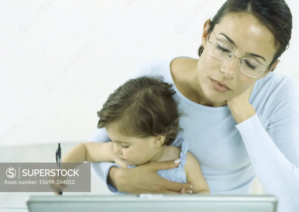 Woman with eyes closed holding little girl drawing with pen
