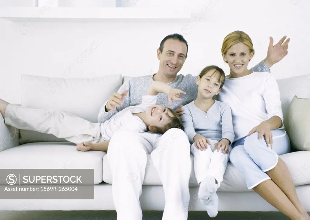 Parents with sitting on sofa with daughter and son, looking at camera