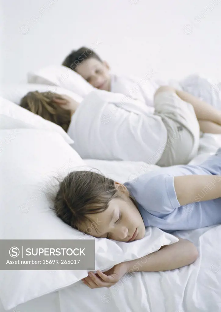 Girl and boys lying down on bed