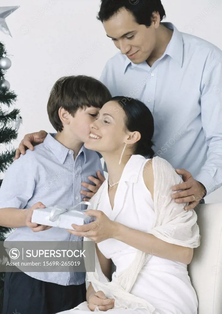 Boy giving gift to mother, father standing behind them