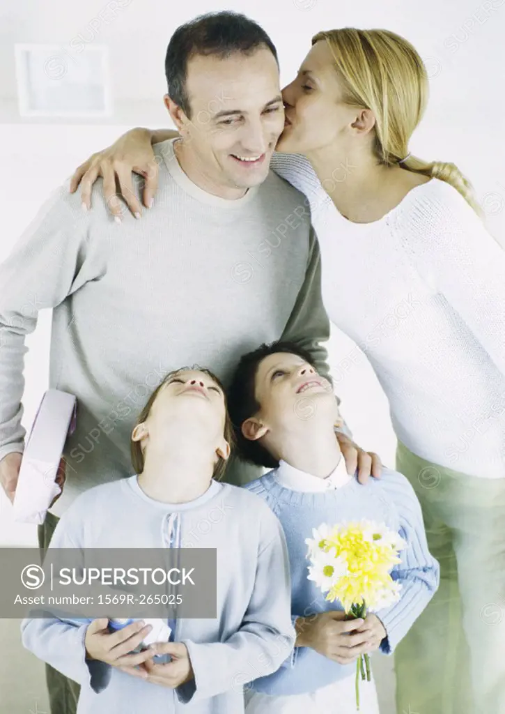 Woman kissing man on cheek, girl and boy looking up with heads back