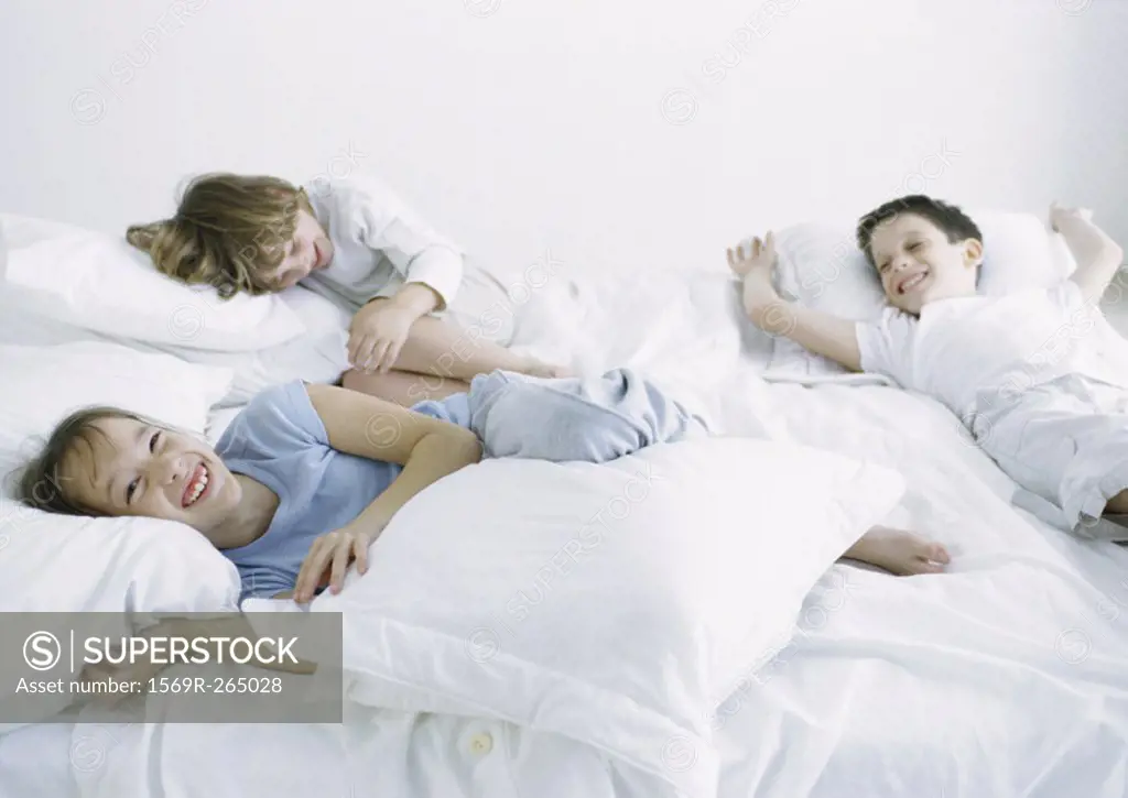 Boys and girl lying on bed laughing and smiling