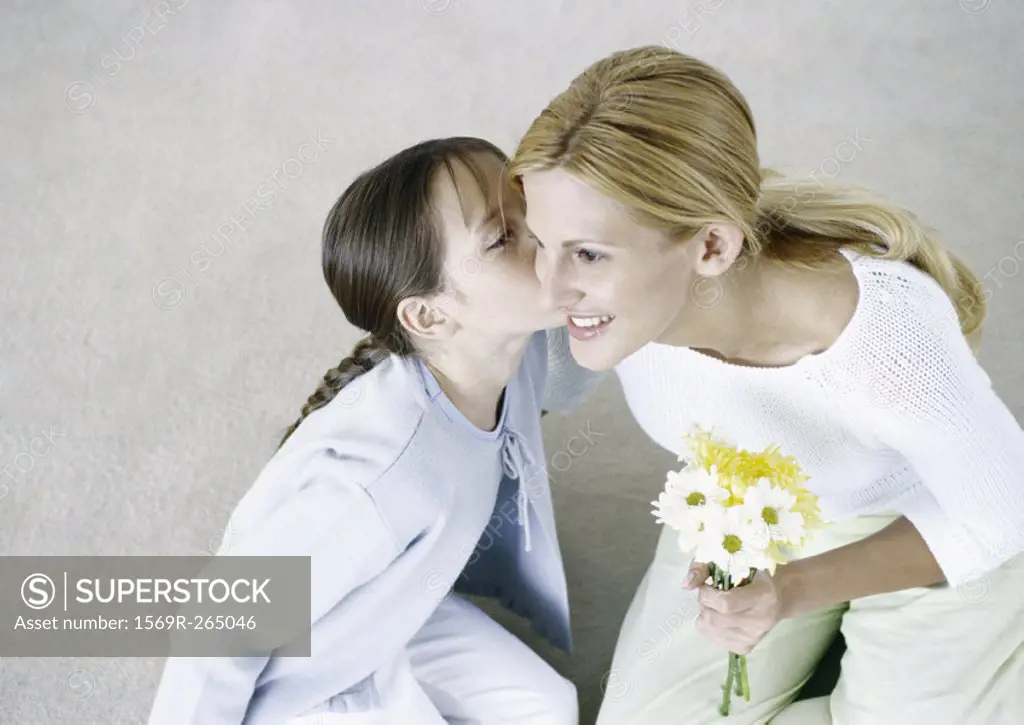 Woman holding bouquet of flowers, girl kissing her cheek