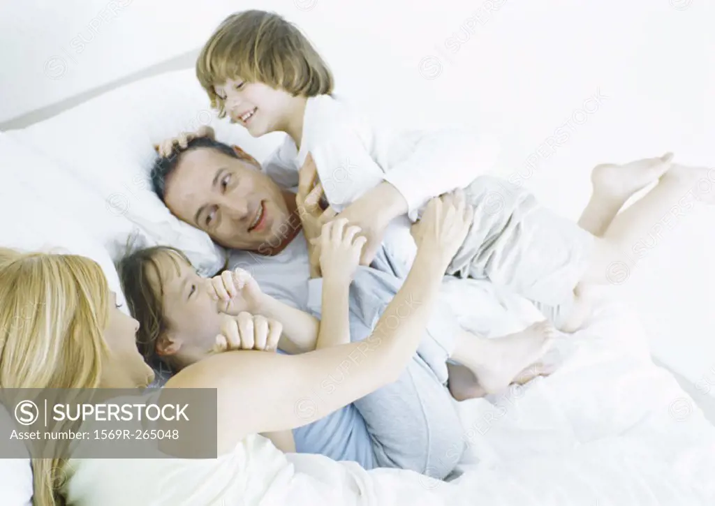 Parents with daughter and son in bed, smiling