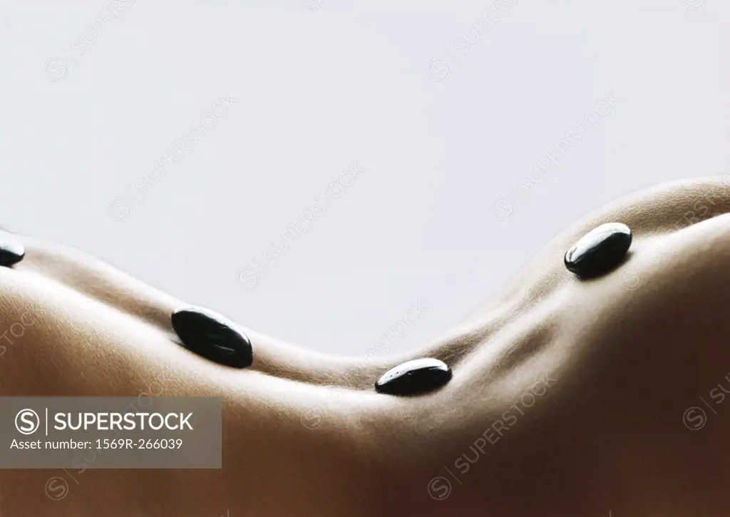 Woman´s back with black stones on spine, close-up