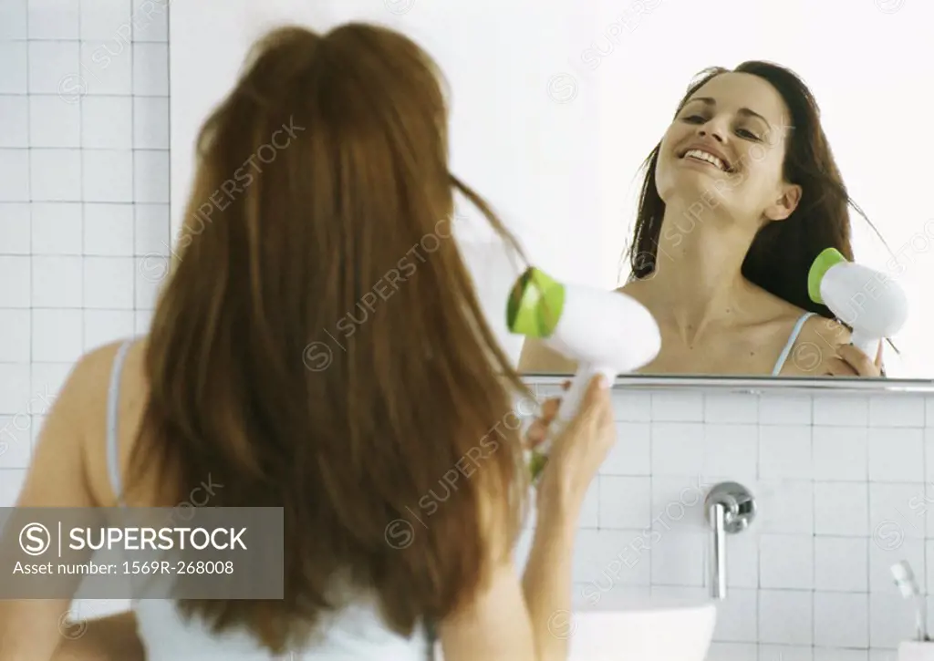 Woman drying hair in front of mirror