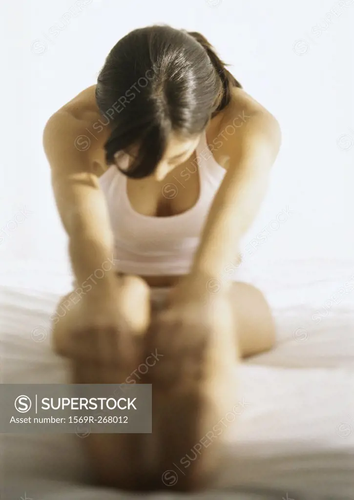 Woman touching toes on bed