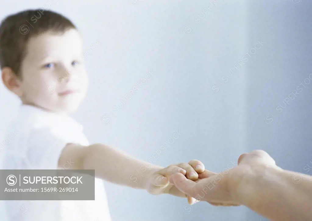 Boy reaching out holding adult hand
