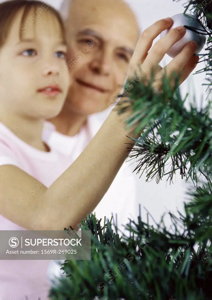 Girl and grandfather decorating Christmas tree