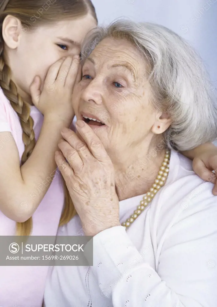 Girl whispering to grandmother