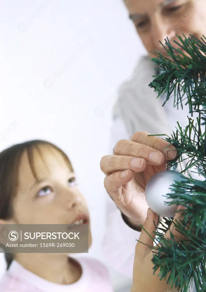 Girl and grandfather decorating Christmas tree