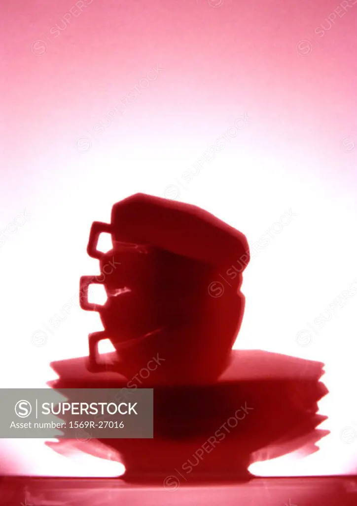 Stack of cups and saucers, red-toned