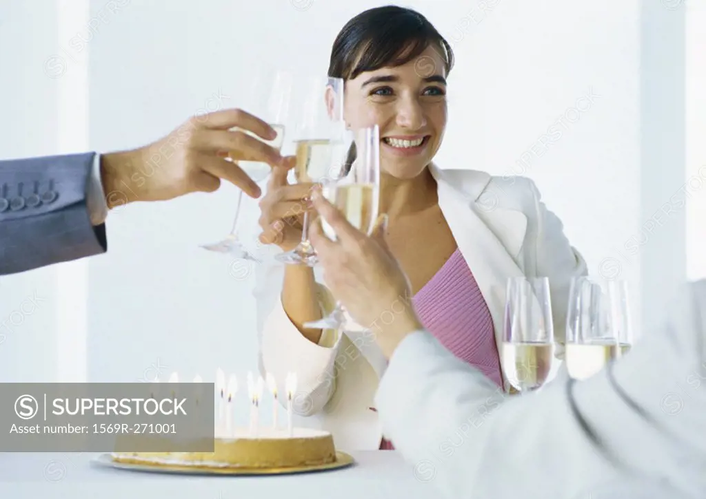 Businesspeople clinking glasses of champagne over birthday cake