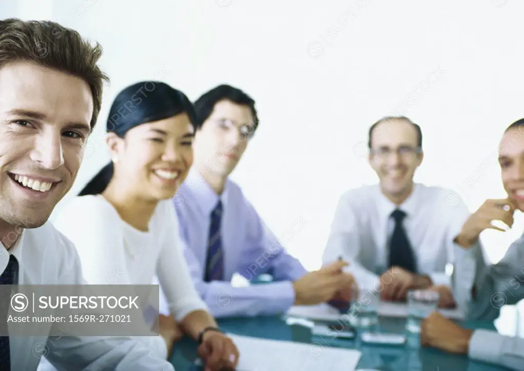 Businesspeople sitting around table, smiling