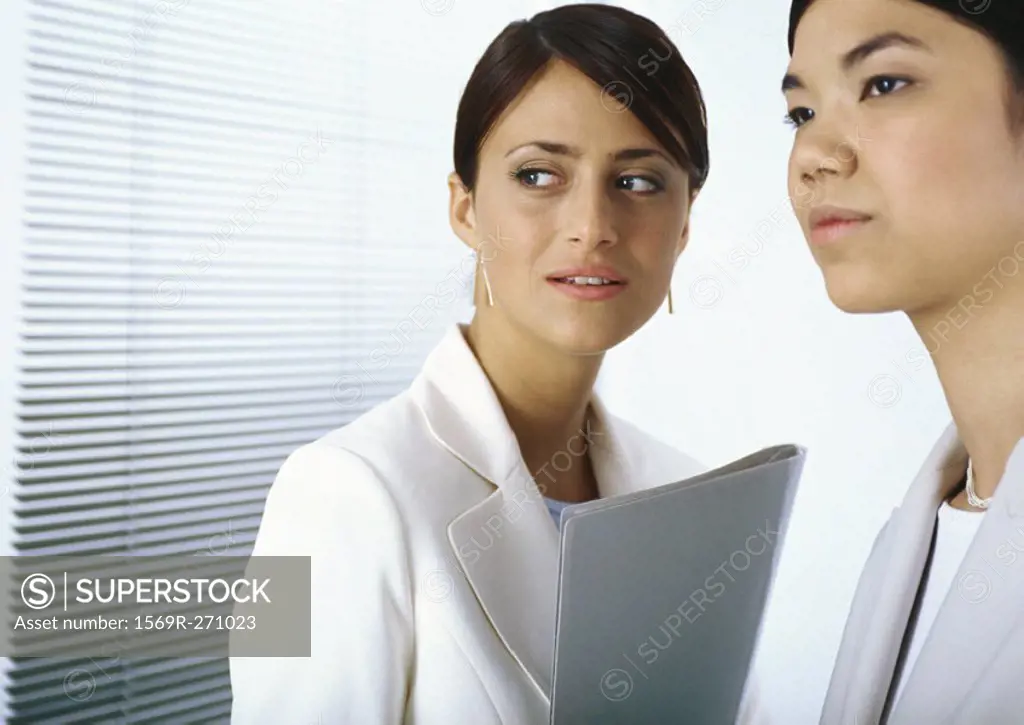 Two businesswomen standing together looking to the side