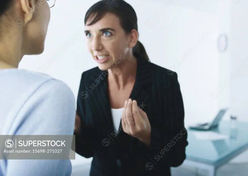 Businesswoman speaking and gesturing angrily to second woman
