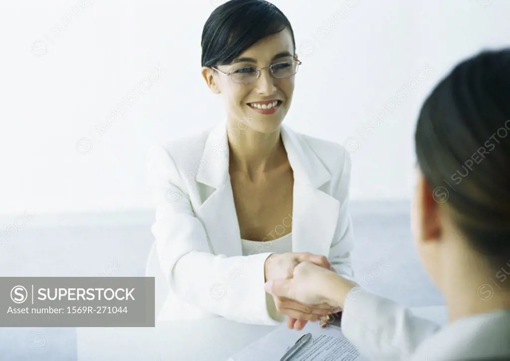 Two women in suits shaking hands