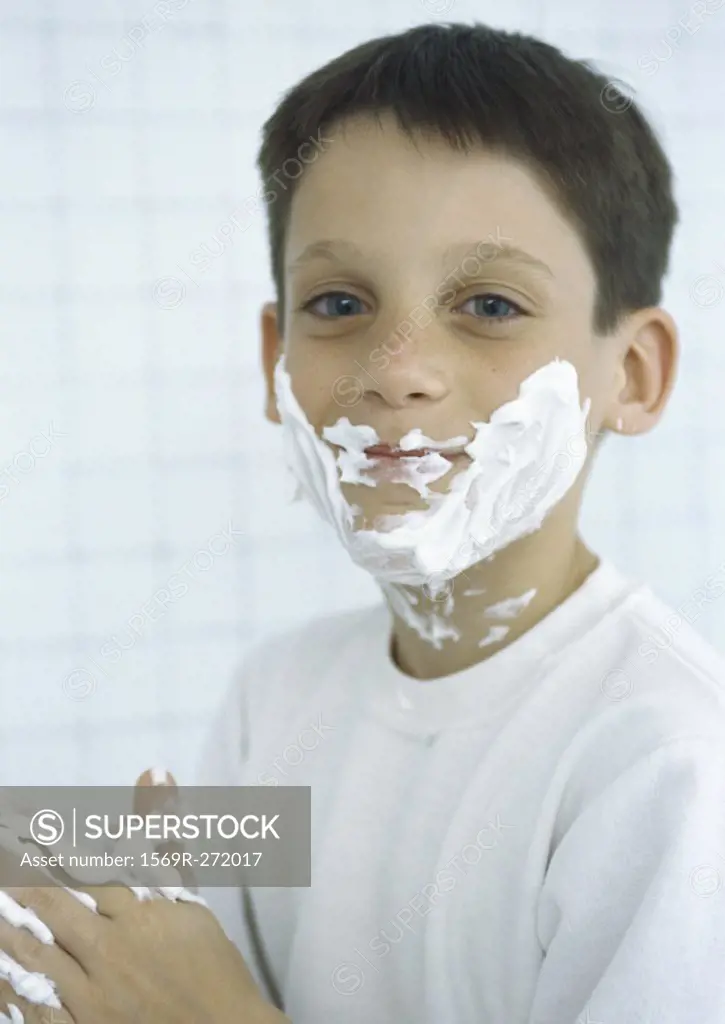 Boy with shaving cream on face and hands