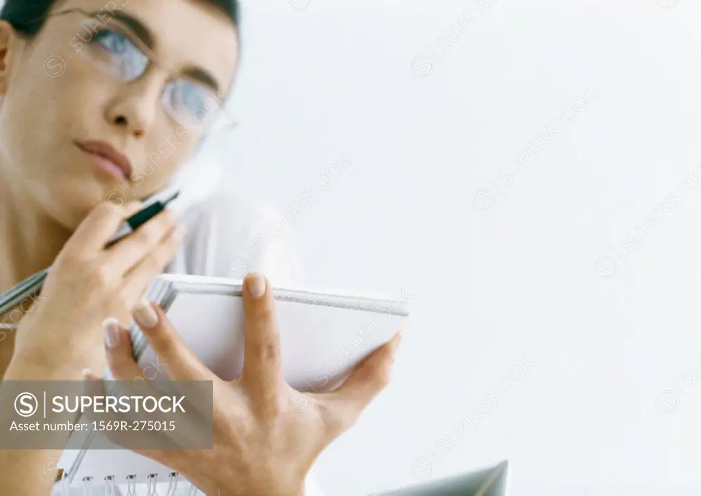 Woman on phone holding notepad and pen
