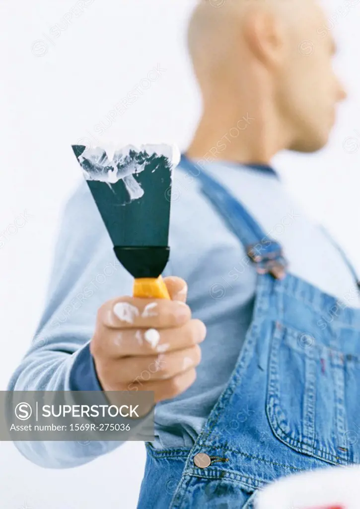 Man holding putty knife, low angle view