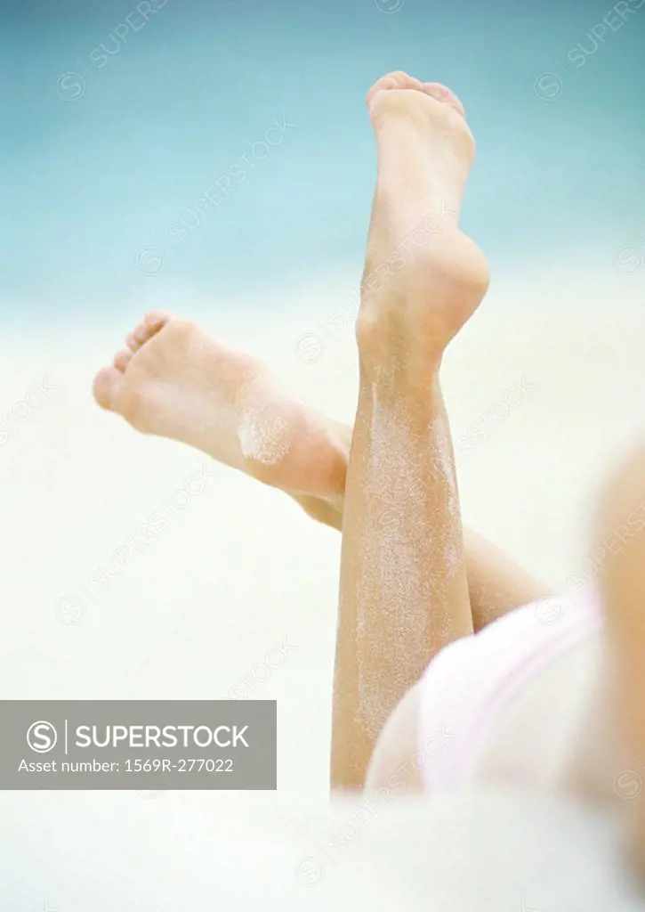 Woman lying in sand, close-up of lower legs