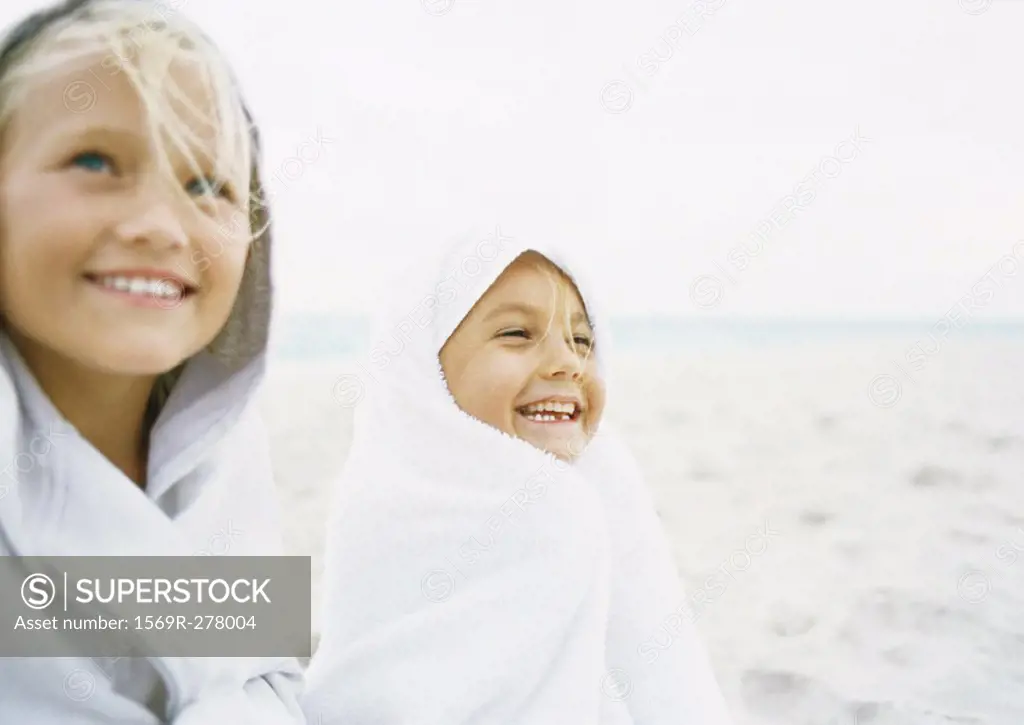 Two girls wrapped up on beach