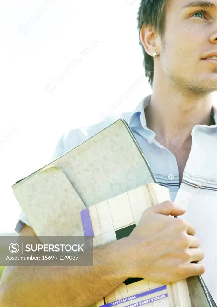 Male student carrying book and folder, partial view, close-up
