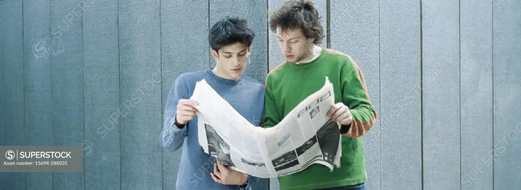 Two young men sharing newspaper