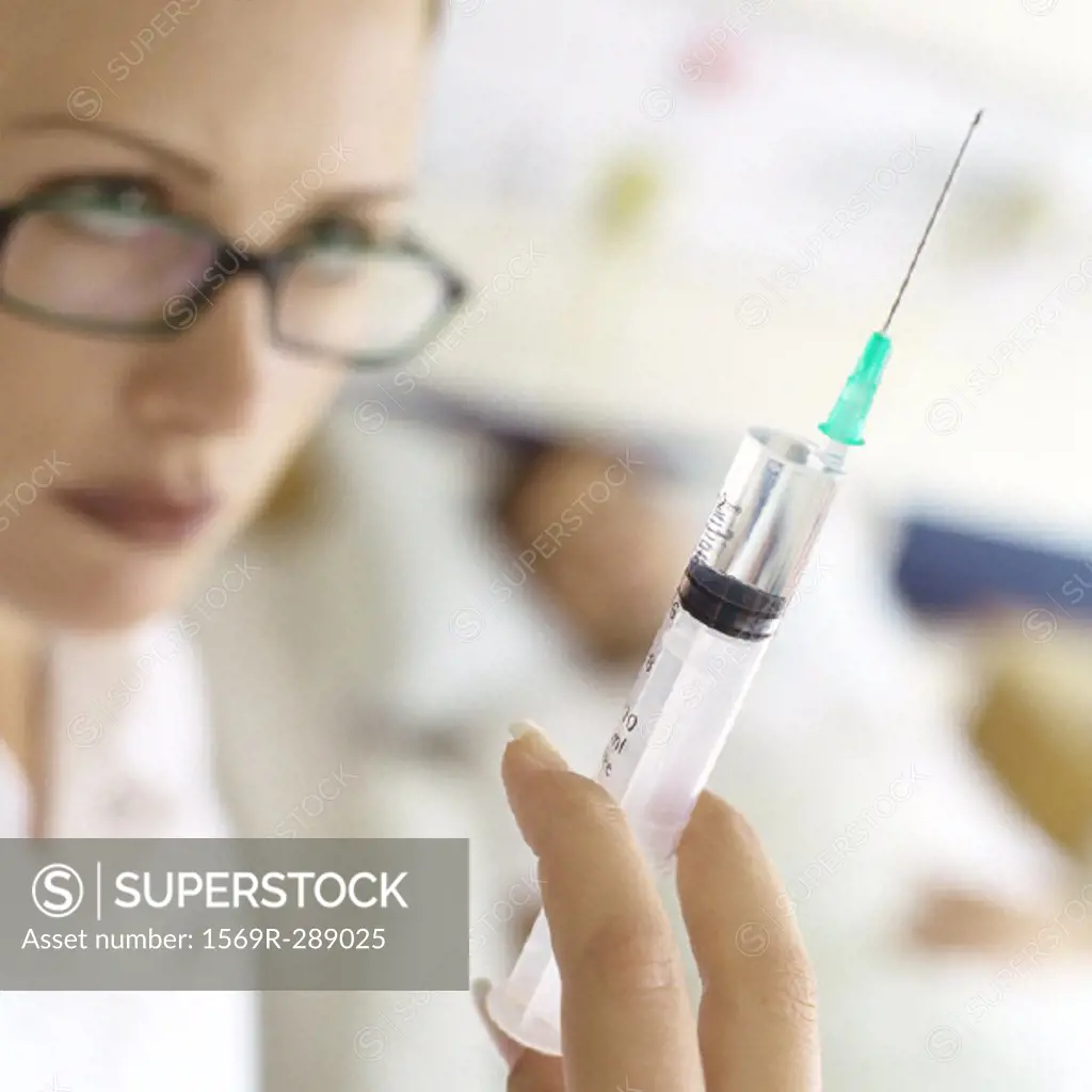 Nurse holding up syringe in front of patient