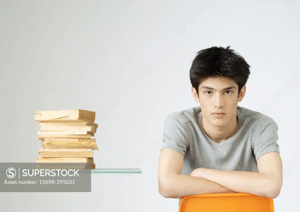 Young man sitting next to stack of books, portrait
