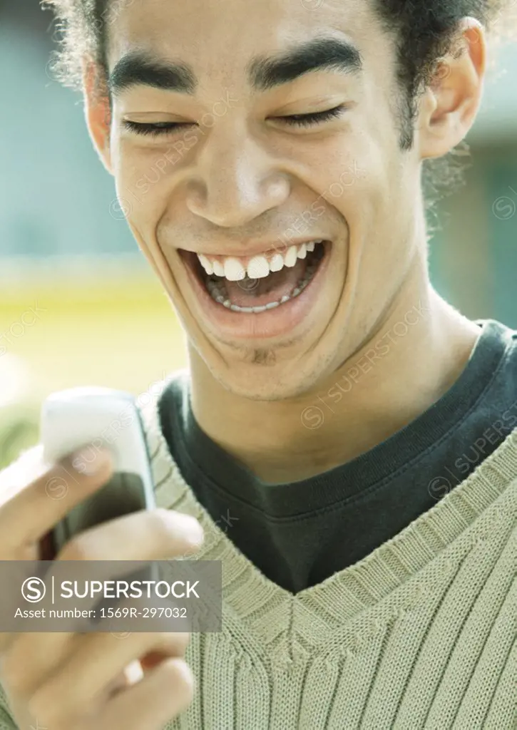 Young man laughing and looking at cell phone, close-up