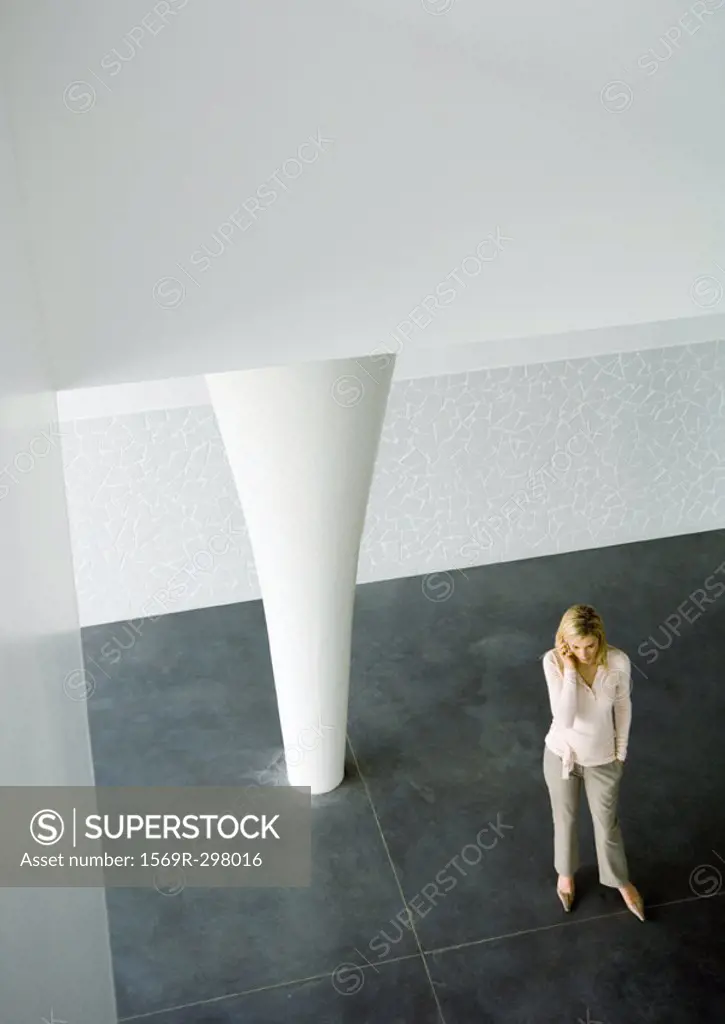 Businesswoman using cell phone in lobby, high angle view