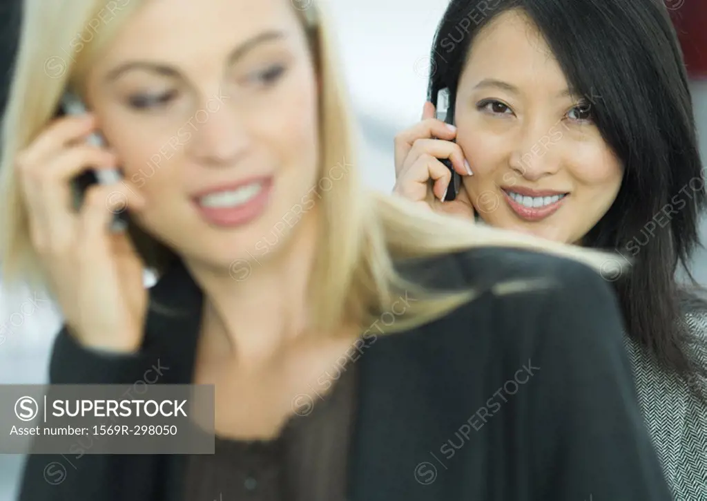 Businesswomen using cell phones, portrait