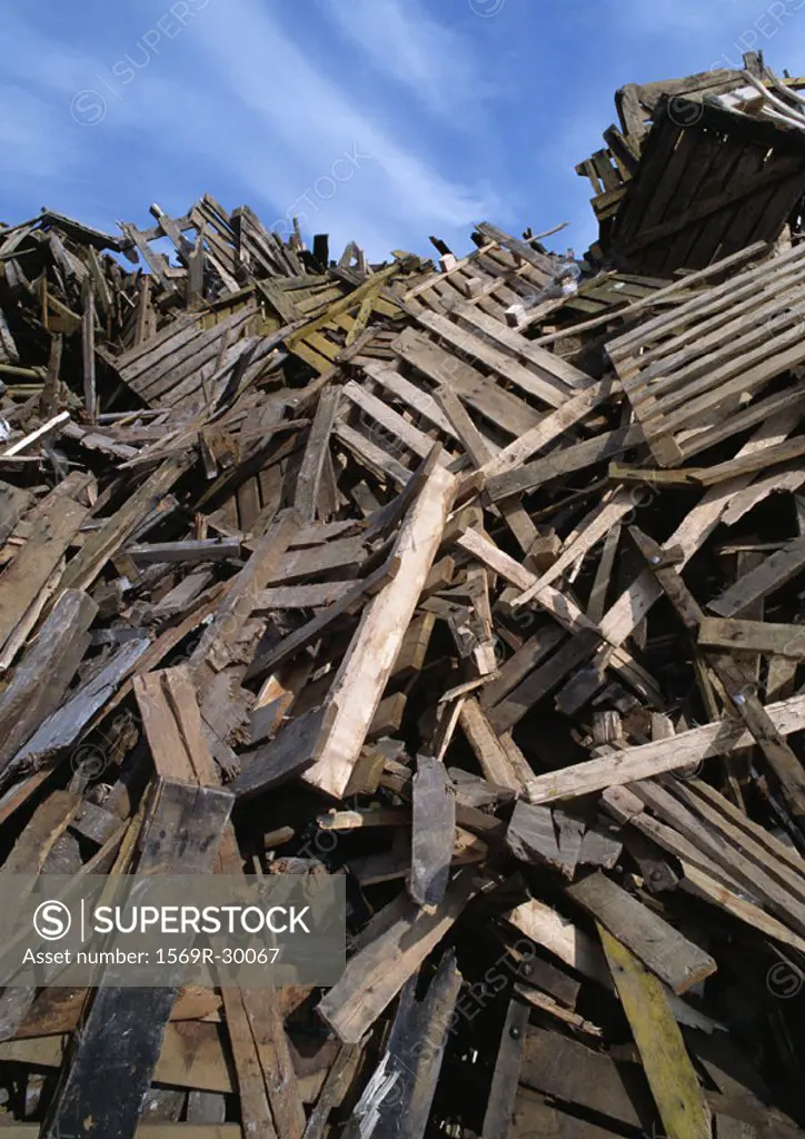 Large heap of wooden planks and pallets, blue sky in background