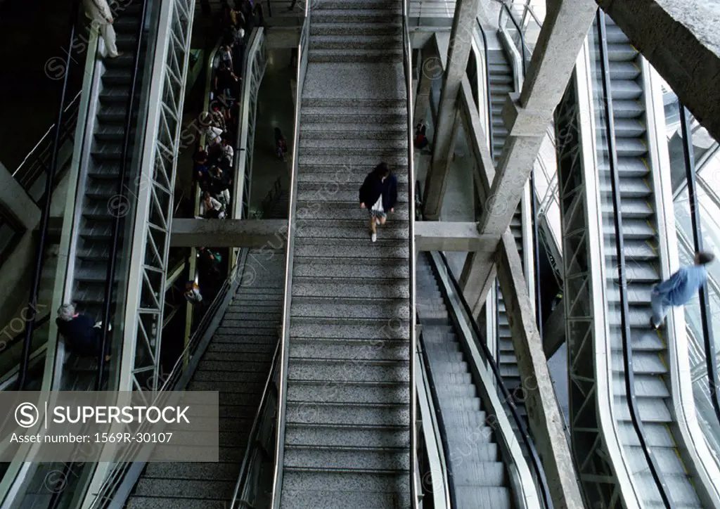 Woman walking down steps in between escalators