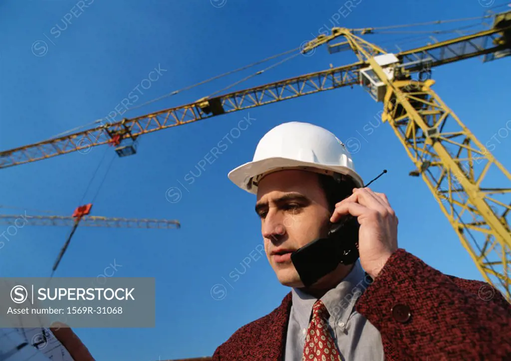 Man wearing hard hat, using cell phone, low angle view