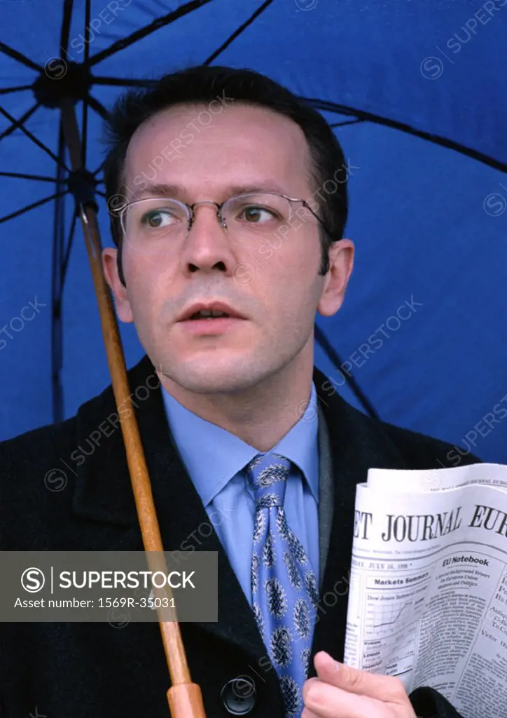 Man holding umbrella and newspaper, portrait
