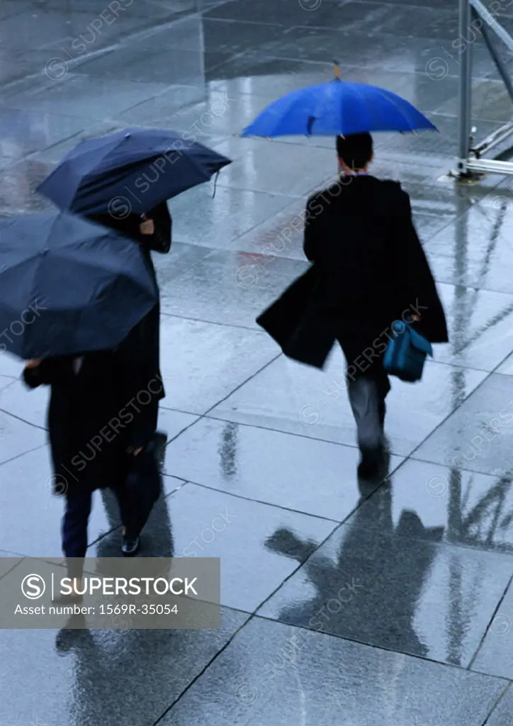 Three people holding umbrellas in street, high angle view
