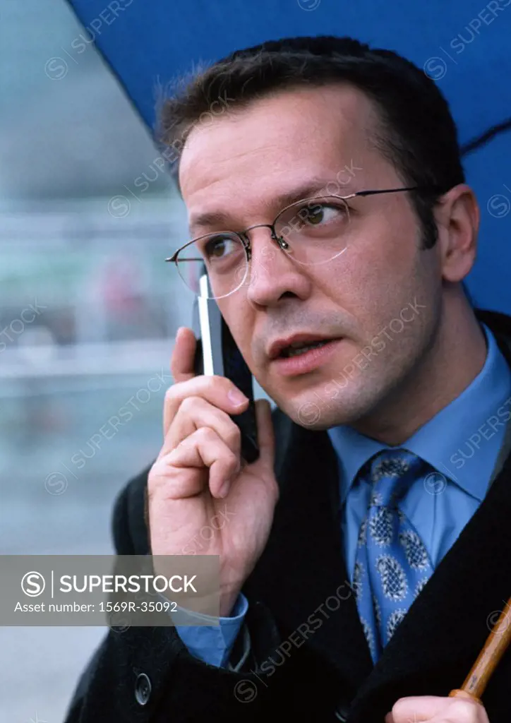 Man holding cell phone and umbrella, portrait