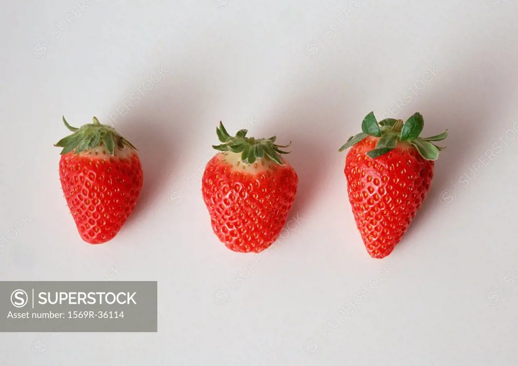 Three strawberries in a row, close-up, white background
