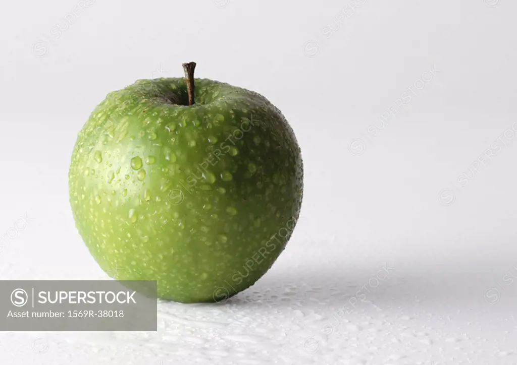 Green apple covered with drops of water, close-up, white background