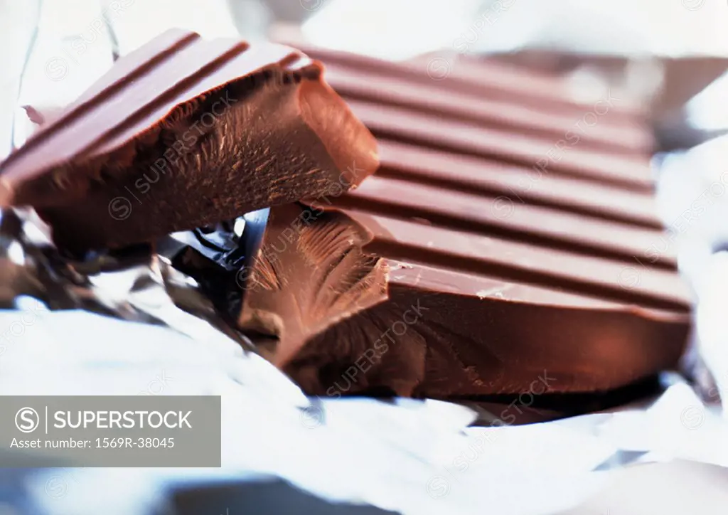 Chunks of milk chocolate, close-up, aluminum foil blurred in background and foreground