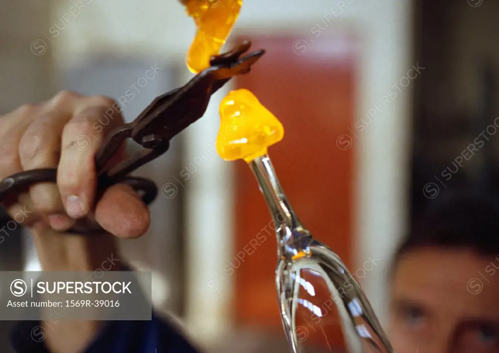 Hand holding scissors, cutting molten glass