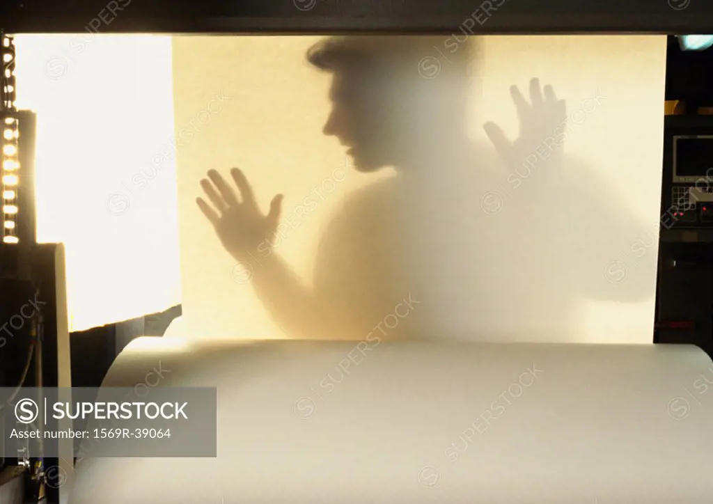 Silhouette of man behind sheet of paper
