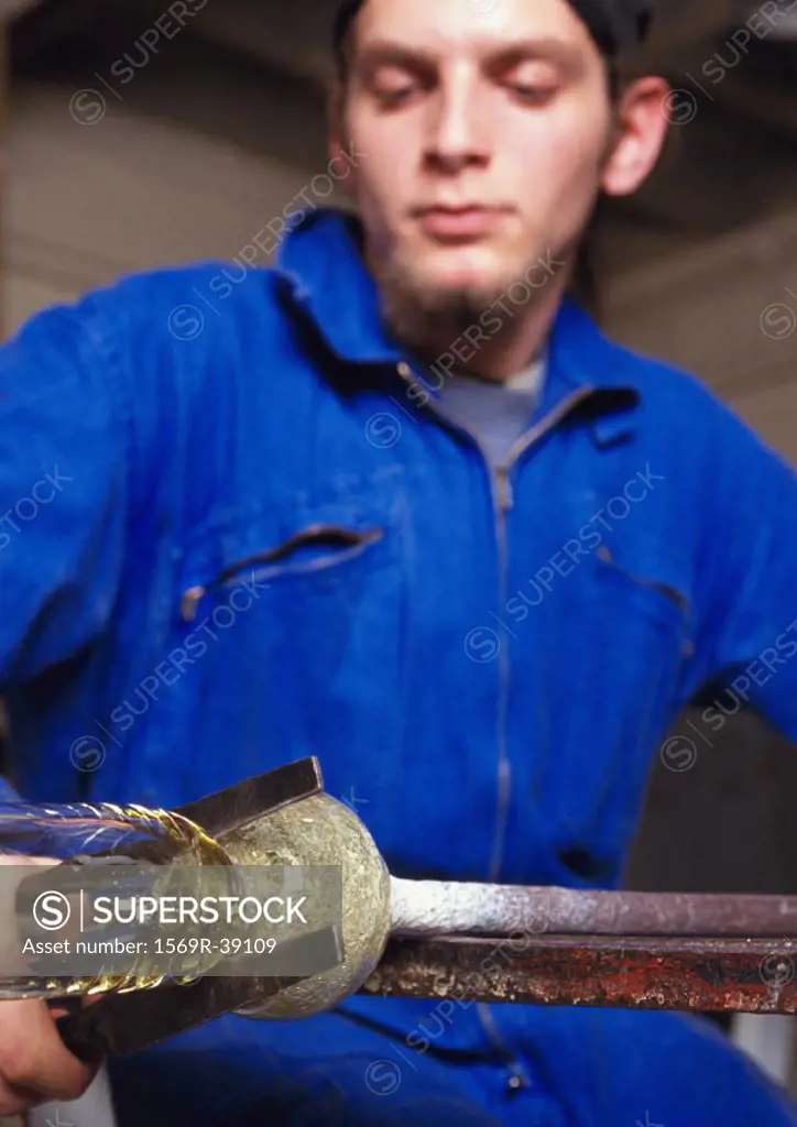 Man in coveralls, working glass