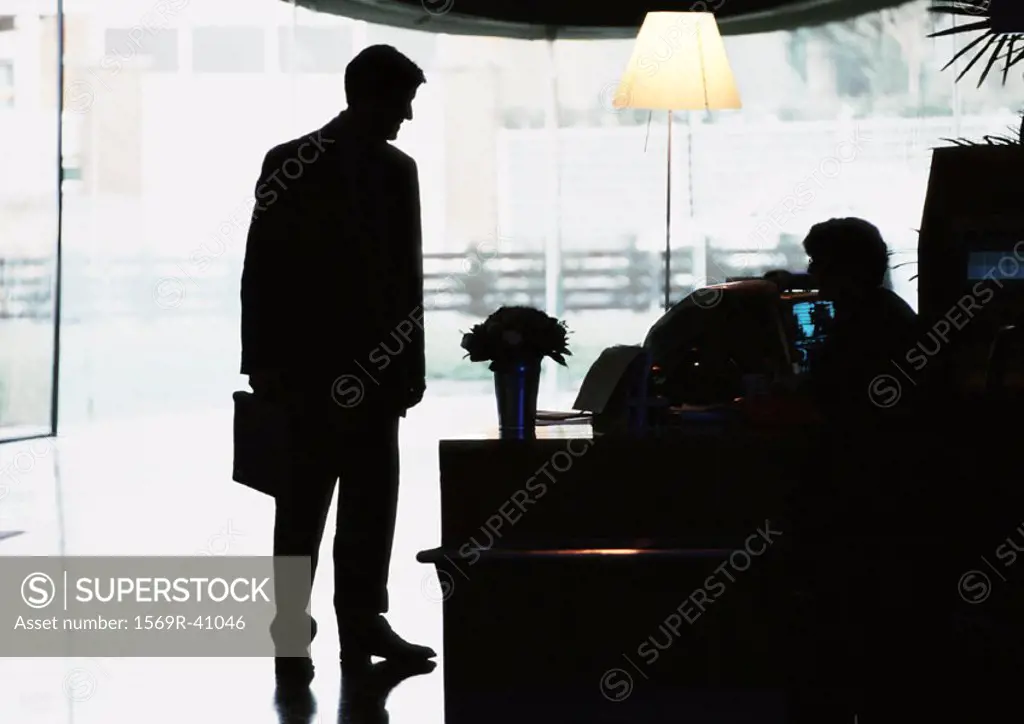 Silhouette of businessman standing by desk