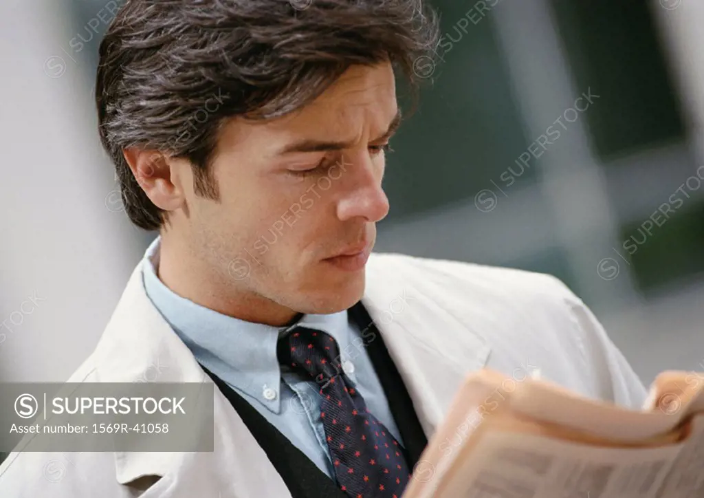 Businessman reading newspaper, portrait