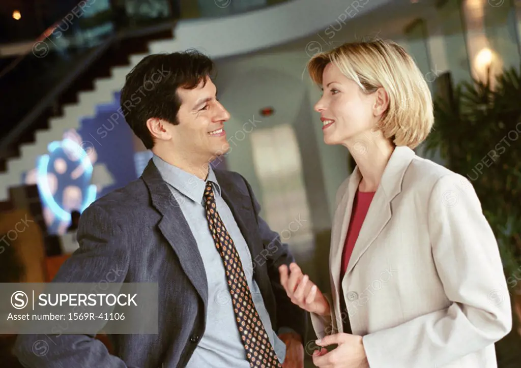 Businessman and businesswoman standing face to face, smiling