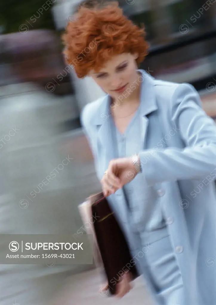 Businesswoman looking at watch, blurred